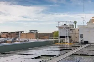 HVAC cooling tower on the roof of a commercial building, surrounded by solar panels.