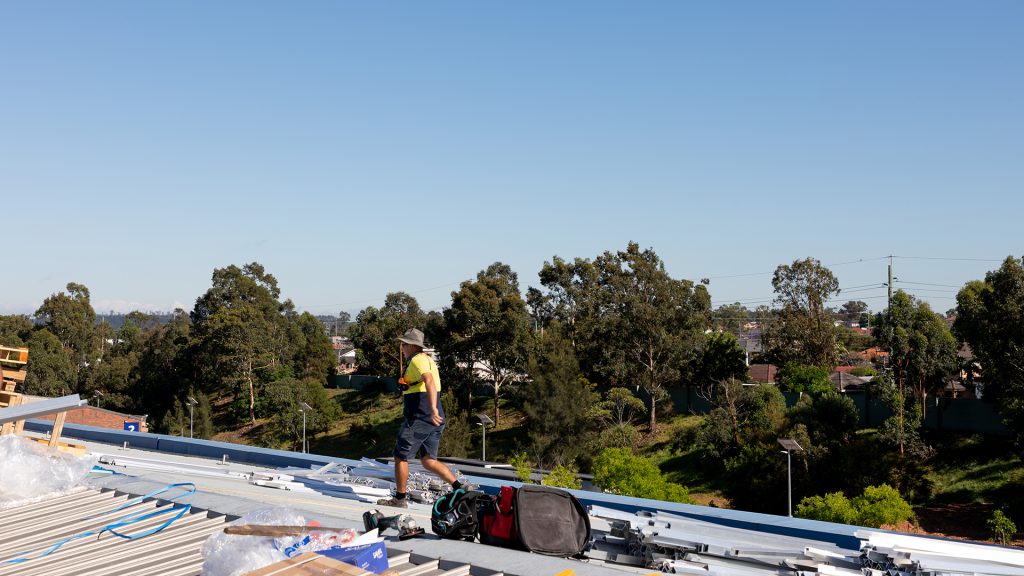 Installers loading materials onto a roof before commencing work.