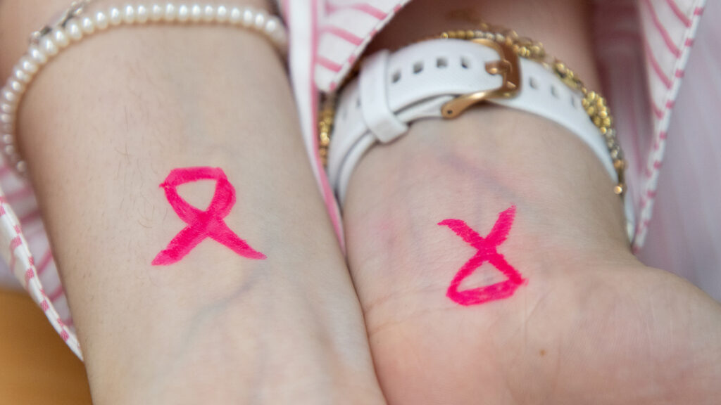 Pink ribbon tattoos drawn on the wrists of two #teamhse memebers.