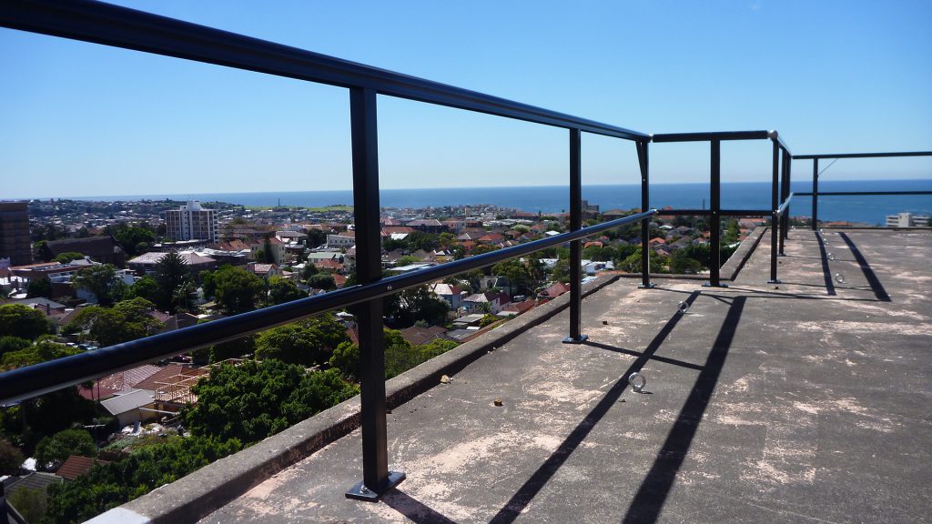 Guardrail installed on top of a tall building overlooking the ocean.