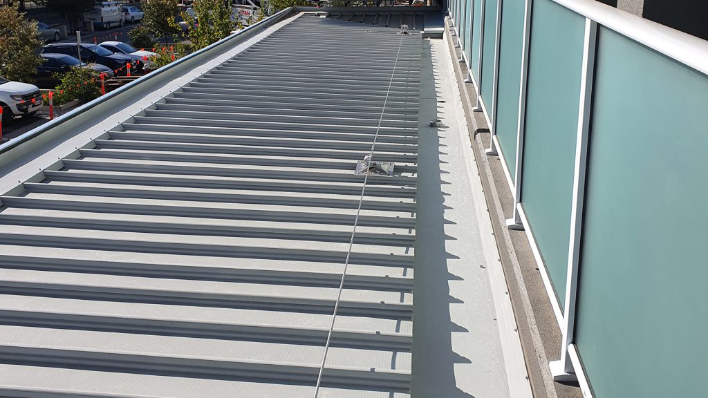 Inspecting a static line system designed for gutter cleaning access over an awning on a commercial building.