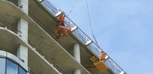 Technicians installing rigid rail abseil system on an under-construction apartment complex.