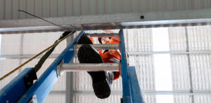 Ascending a portable ladder onto a metal roof.