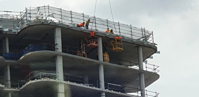Workers installing an abseil system on an under-construction apartment building.