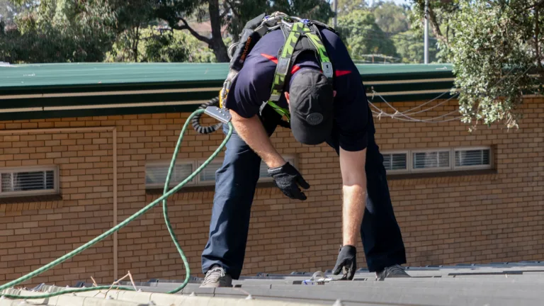 Worker beding over a roof anchor point to check whether it is safe to connect to.