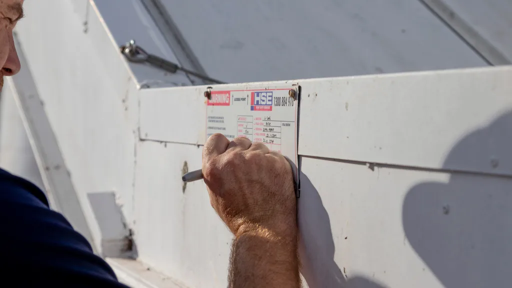 HSE recertification technician updating a system compliance plate following an inspection.