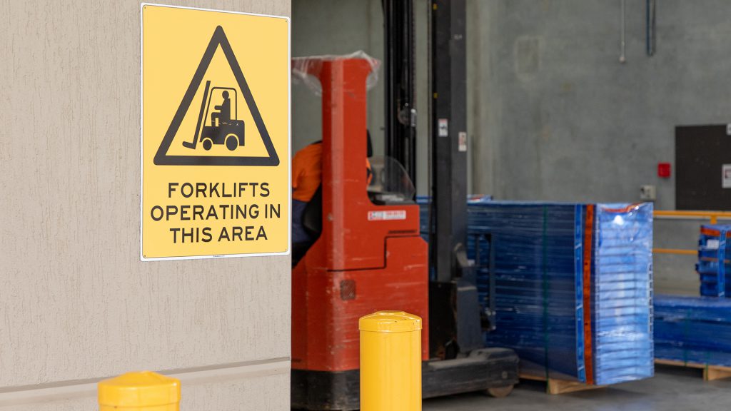 Bright yellow sign notifying workers that forklifts may be operating in the area.