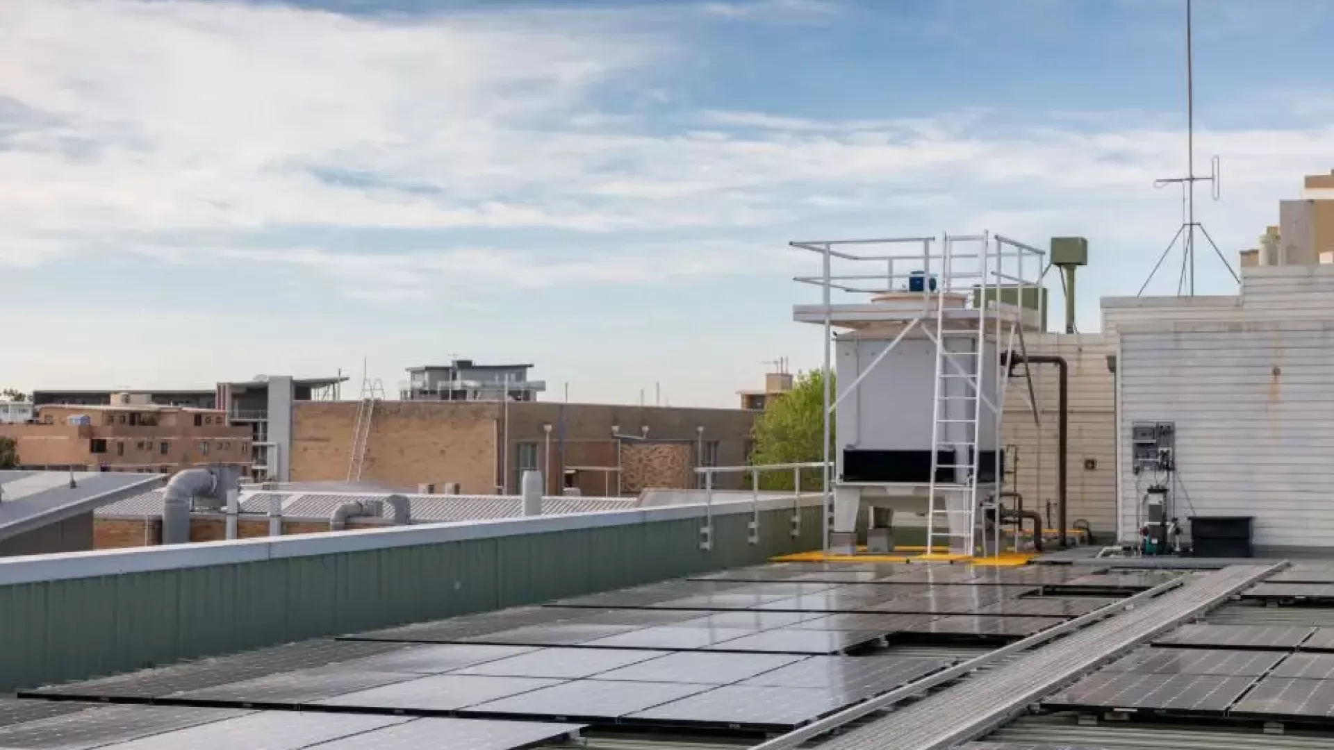 HVAC cooling tower on the roof of a commercial building, surrounded by solar panels.