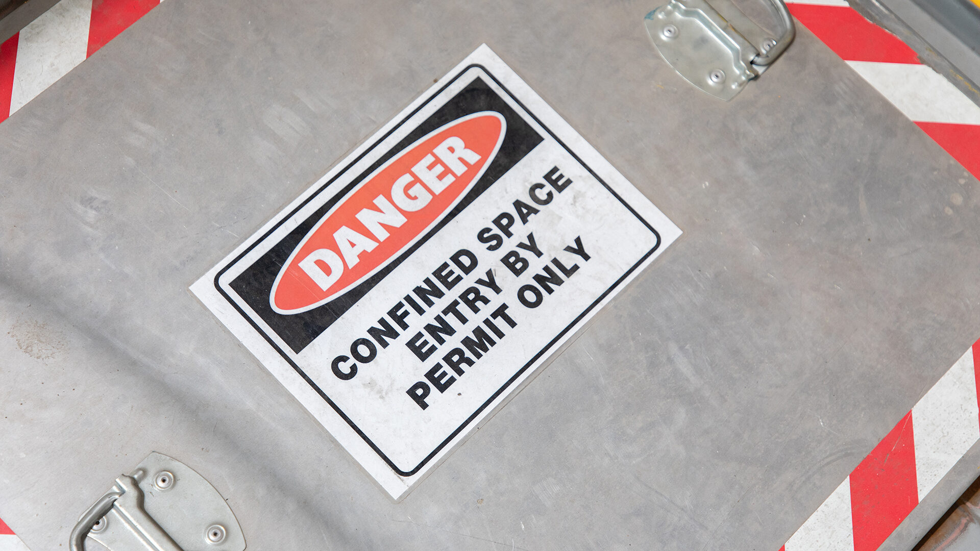 Danger confined space warning on a manhole cover.