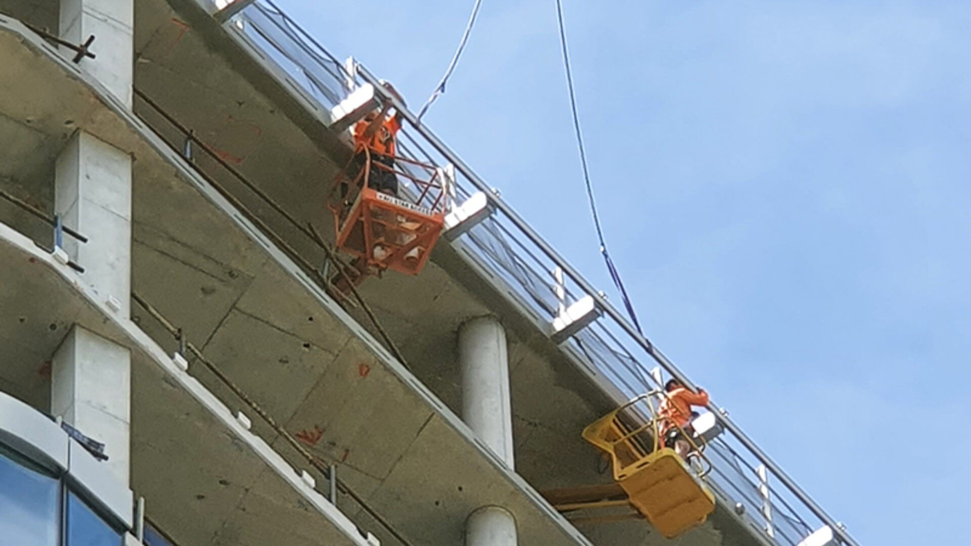 Technicians installing rigid rail abseil system on an under-construction apartment complex.