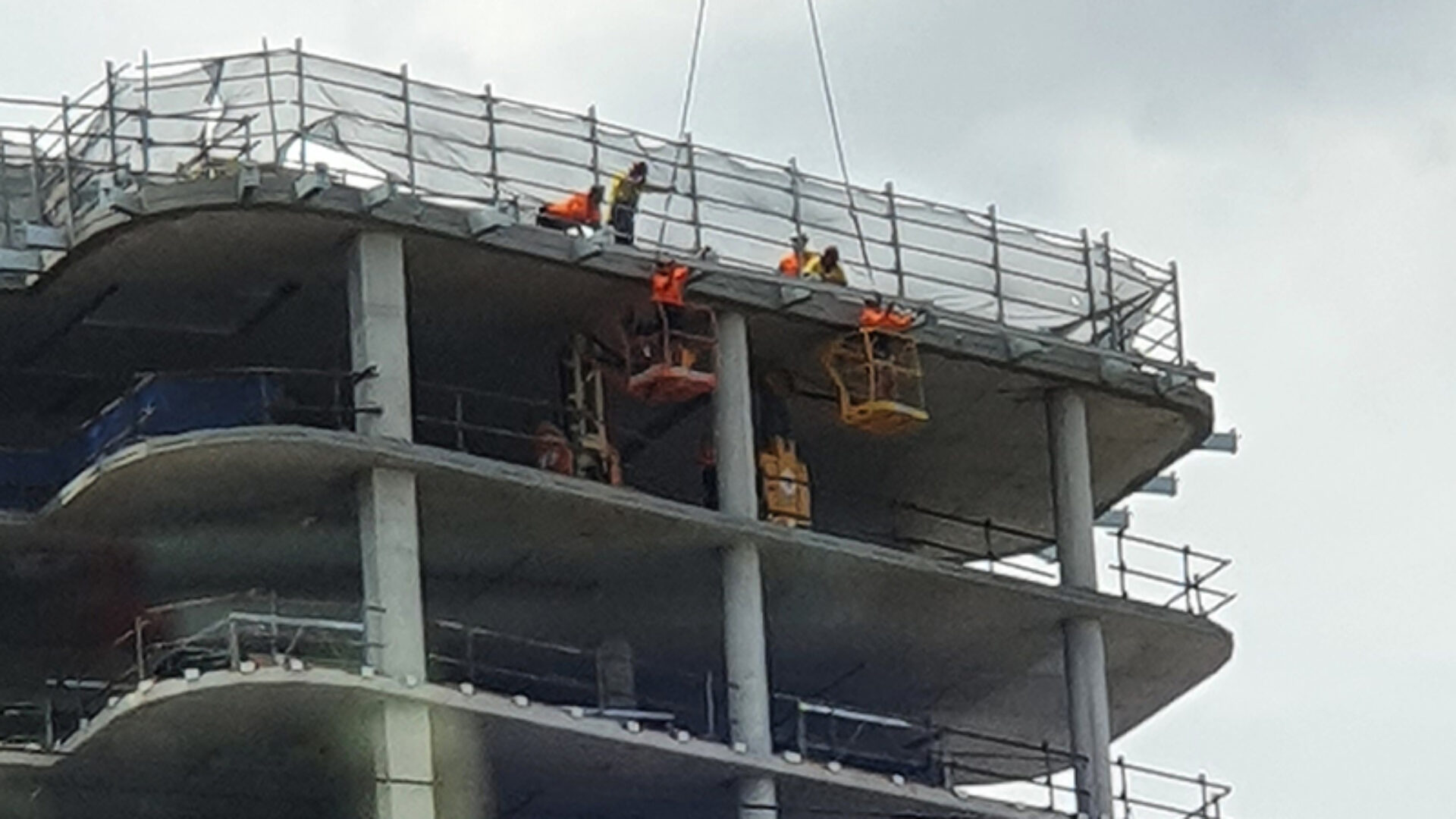Workers installing an abseil system on an under-construction apartment building.