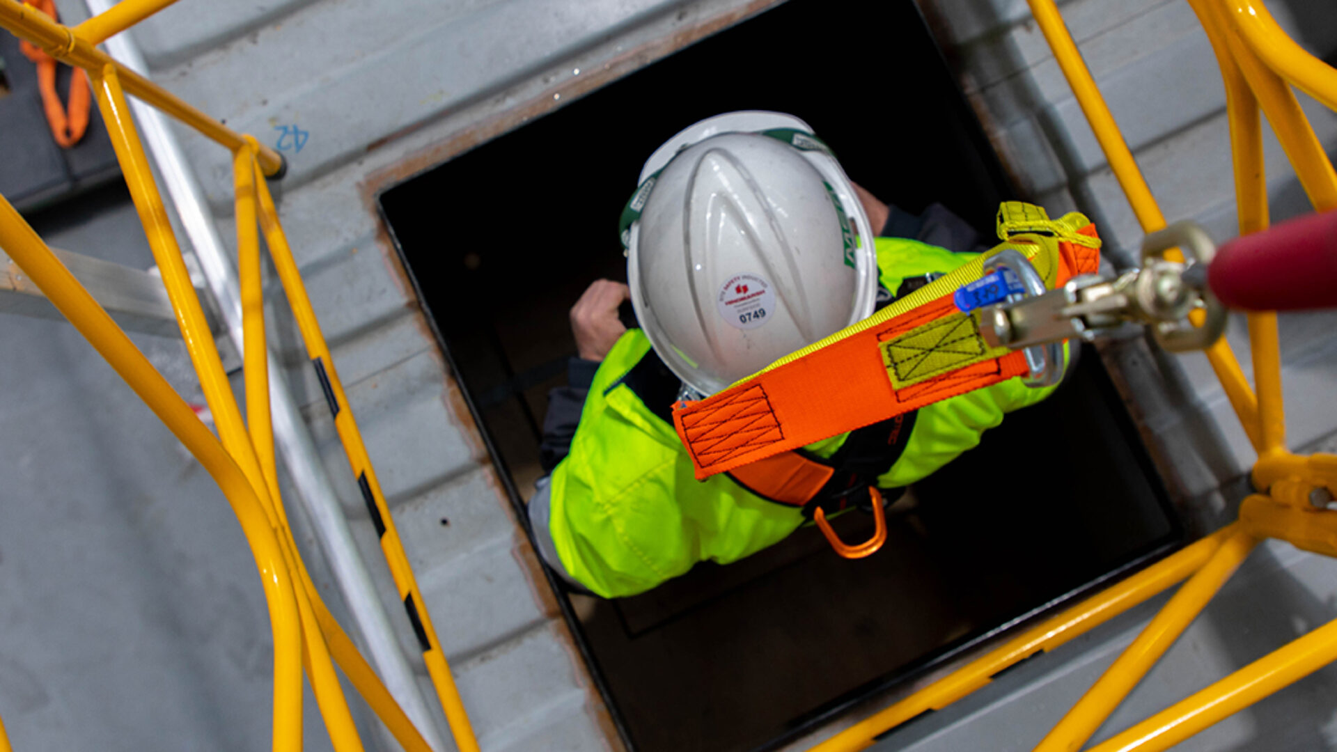Worker being lowered through an entry manhole into a confined space