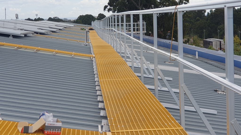 Levelled walkway and guardrail long a pitched warehouse roof.