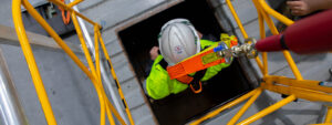 Worker being lowered through an entry manhole into a confined space