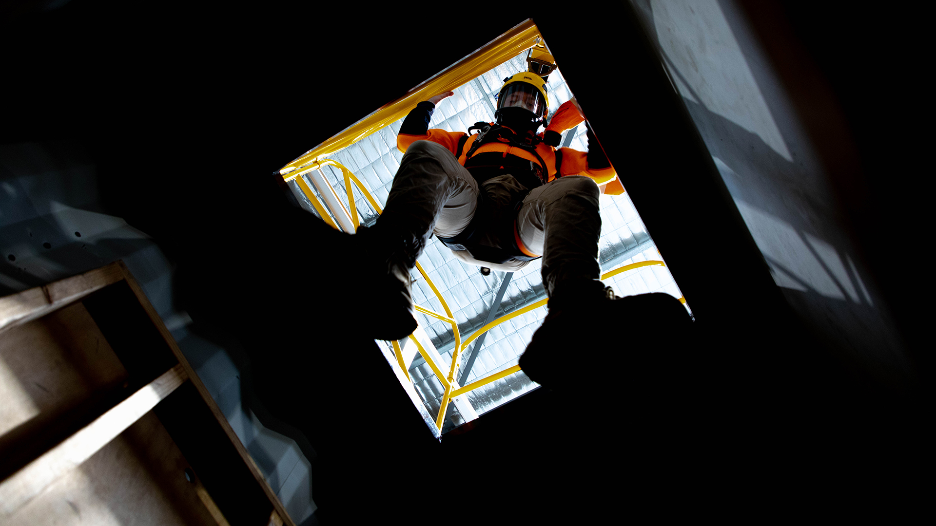 Worker, wearing breathing apparatus, entering a confined space.
