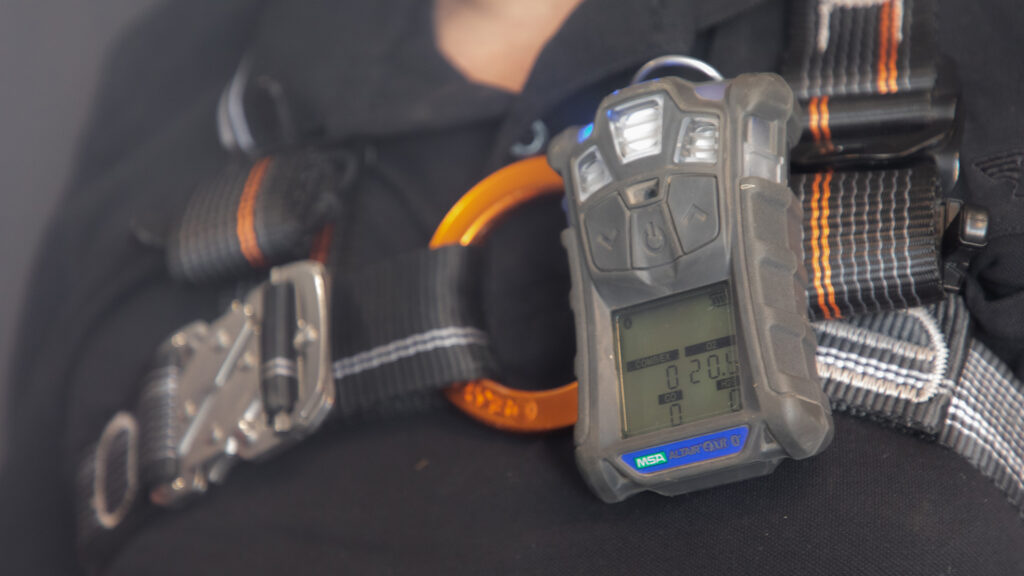 Gas detector attached to a worker's harness.