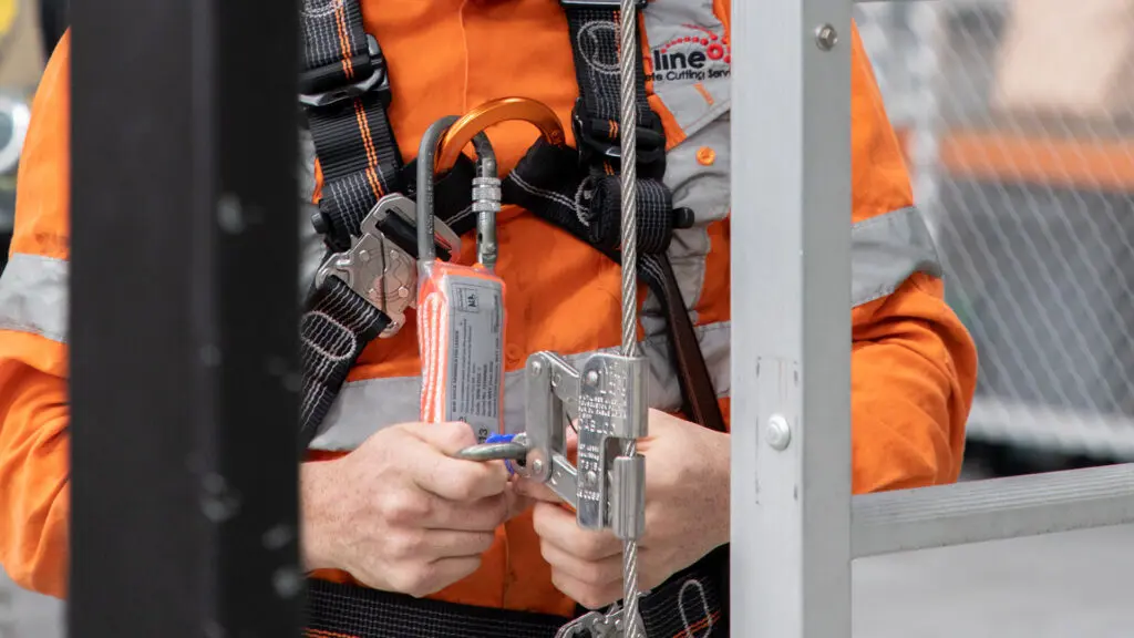 Worker connecting their harness to a vertical ladder line using a shuttle.