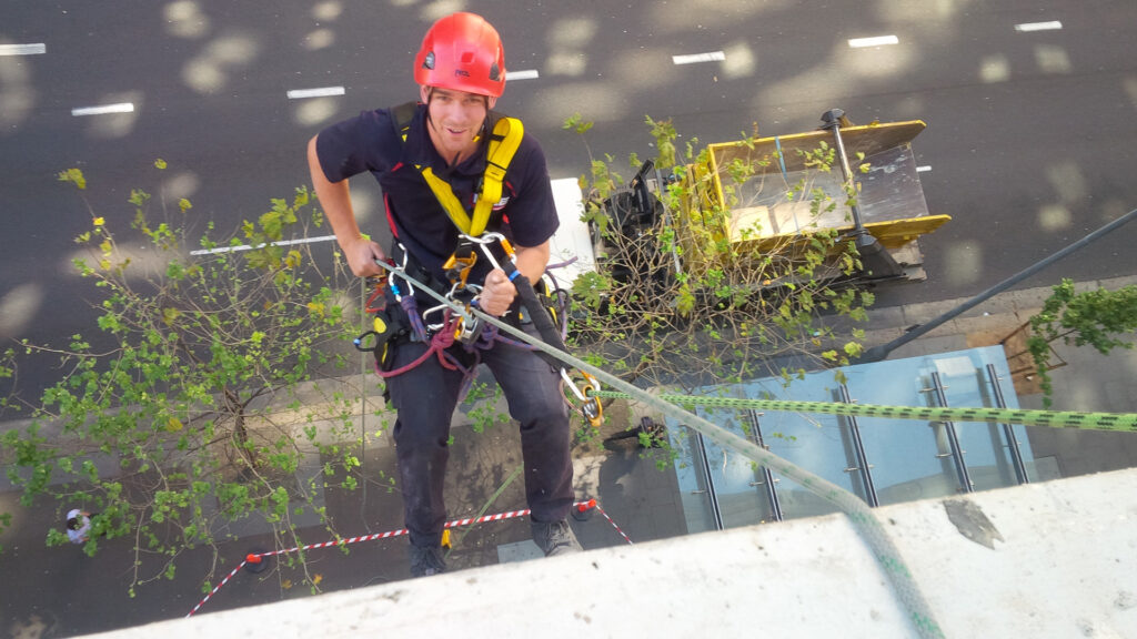 Worker descending down a building's facade using rope access equipment.