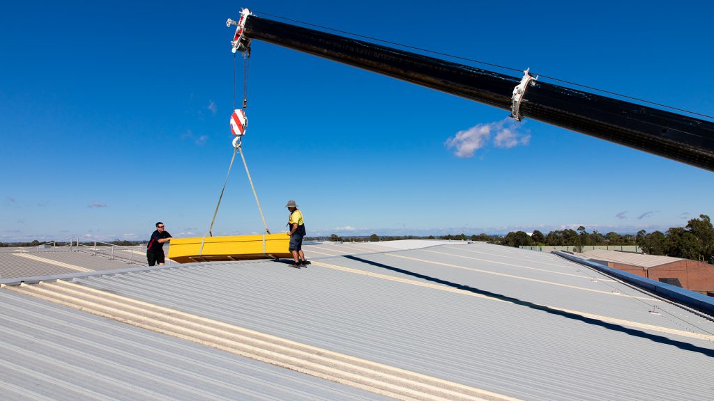 Lifting FRP walkway into a roof using a heavy crane.
