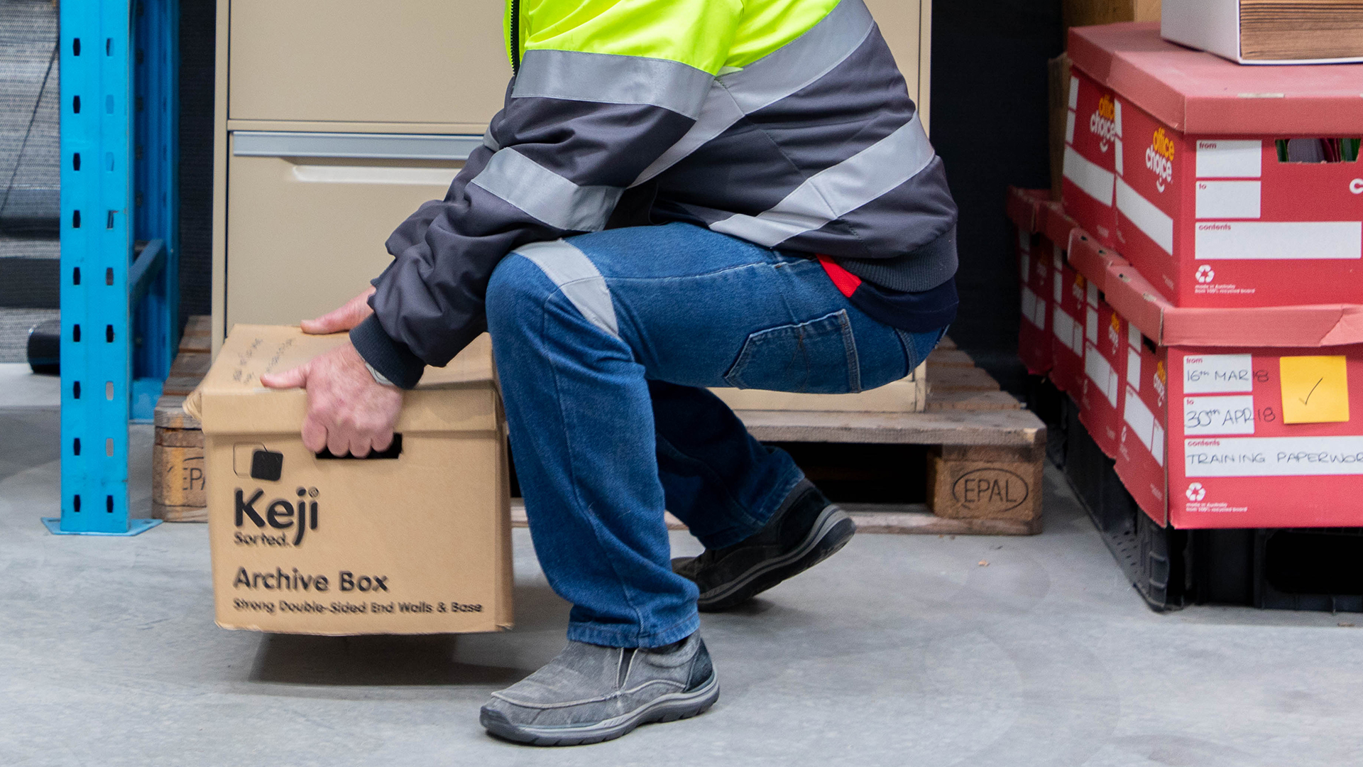 Participant lifting an archive box using safe manual handling techniques.